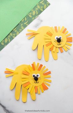 two paper lion cut outs sitting on top of a white marble table next to a green ribbon