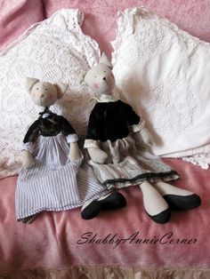 two stuffed animals sitting on top of a bed next to pillows and lace covered sheets