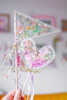 a hand holding a pink and white pinwheel with lots of confetti on it