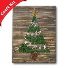 a christmas tree made out of grass on top of a wooden board with the words craft kit written below it