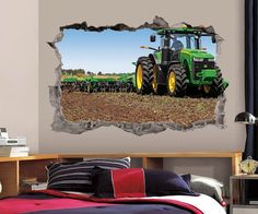 a green tractor is in the middle of a field through a hole in a wall