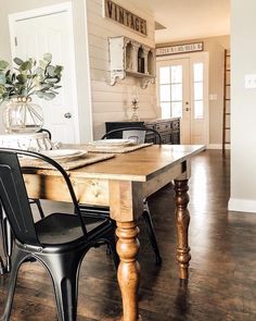 a dining room table with two chairs and a vase on top of it in front of a doorway