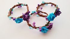 two bracelets made out of twigs with flowers and leaves on the ends, sitting on a white surface