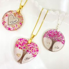 two necklaces that have hearts and trees on them, one with pink sprinkles