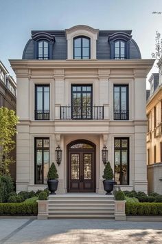 Front view of a grand neoclassical home with tall windows and classic columns. The charm of modern neoclassical architecture combines timeless elegance with contemporary style for a home that whispers both nostalgia and innovation. European Mansion, Neoclassical Home, Individual House, Modern Neoclassical, Modern Home Style, Exterior House Design, Mansard Roof