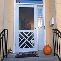 an orange pumpkin sitting in front of a white door with wrought iron railings on the steps