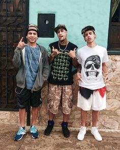 three young men standing next to each other in front of a blue wall and door