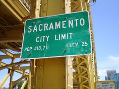 a green street sign sitting on the side of a yellow bridge