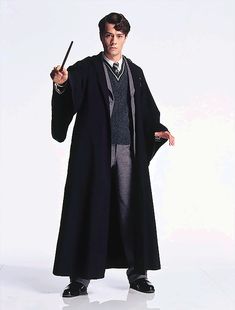 a man in a harry potter costume holding a wand and pointing to the side with his right hand