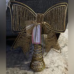 a gold metal bow on top of a table next to a black chair with a book in it