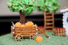 a miniature wagon filled with pumpkins on top of a green field next to trees