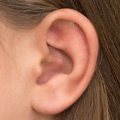 a woman's ear with two tiny gold studs