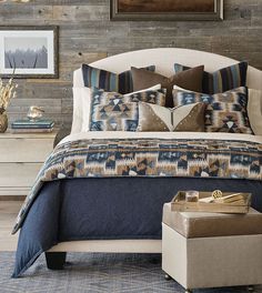 a large bed with blue and brown pillows on top of it next to a dresser