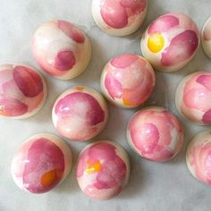 pink and yellow painted eggs sitting on top of a white countertop next to each other