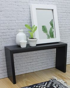 a black and white table with a potted plant on it next to a mirror