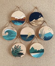 six wooden wall hangings with different designs on them, each depicting the ocean and mountains