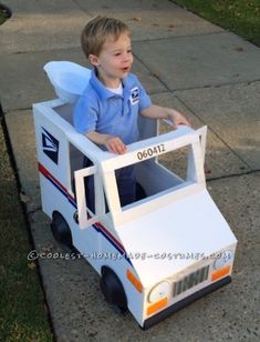 a young boy sitting in a toy firetruck on the side of the road