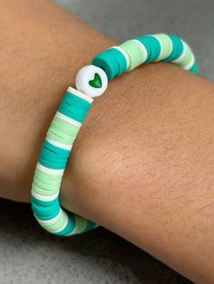 a close up of a person's arm wearing a bracelet with green and white beads