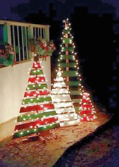 lighted christmas trees on the side of a house in front of a window at night