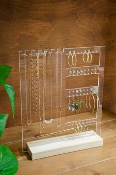 a clear acrylic display case holds earrings and bracelets on a wooden table