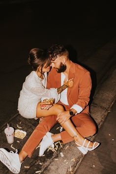 a man and woman sitting next to each other on the ground eating food from their hands