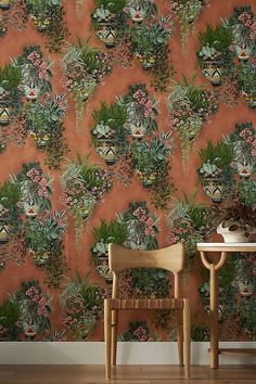 an orange wallpaper with green leaves and pink flowers in pots on top of it