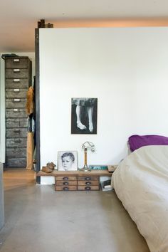 a bedroom with a bed, dresser and pictures hanging on the wall in front of it