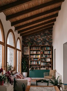 a living room filled with lots of furniture next to large windows and a book shelf