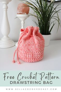 a crochet drawstring bag sitting on top of a table next to a potted plant