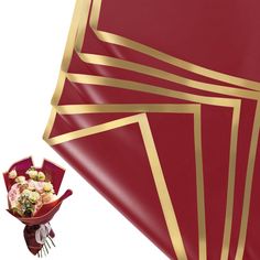 a bouquet of flowers sitting on top of a red and gold cloth covered tablecloth