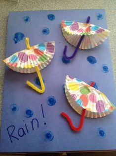 three paper umbrellas are sitting on top of a blue card with the words rain