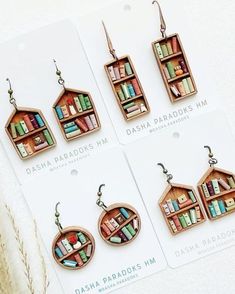 four different bookshelf earrings are shown in three different colors and styles, each with bookcases