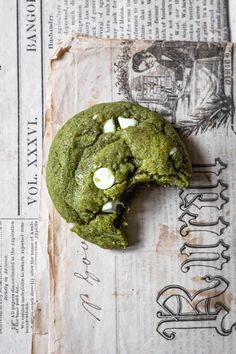 a green cookie with white chocolate chips is on top of an old piece of paper