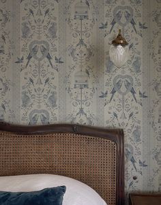 the headboard of a bed in front of a wallpaper with birds on it