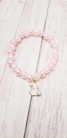 This beautiful pearl bead and bunny Charm bracelets is the perfect gift for someone special. The charm is made of high-quality beads. This makes an excellent gift for yourself or your friends and family members.  The bracelet is made with a high-quality beads that is eco-friendly, durable, and anti-inflammatory. It won't leave your skin green due to marks. Product Details: - Material: stretchy string,pink and gold beads,heart charm and initial charm pearl beads 8 mm.  Please reach out to me for customizations.  Product Packaging: ----------------------------- The bracelets will come in a beautiful organza bag; you can choose this as a gift for someone special. Chocking Hazard Warning, please remember that these beads are a chocking hazard. Do not leave bracelet on during nap time or bed ti Cute Handmade Pearl Bracelet Gift, Pearl Beaded Bracelets With 8mm Beads As A Gift, Pearl White Beaded Bracelet Gift, Pearl White Beaded Bracelet For Gift, Cute Beaded Pearl Bracelet Gift, Cute Beaded Pearl Bracelet As A Gift, Cute Beaded Pearl Bracelet As Gift, Pearl Charm Bracelet With Round Beads As Gift, Pearl Beaded Bracelets With Pearl Drop As Gift