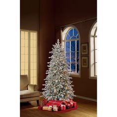 a white christmas tree in a living room next to a window with presents under it