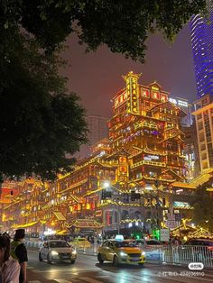 a busy city street at night with cars and buildings lit up in bright lights on both sides