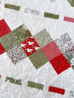 a close up view of a quilted table runner with red, green and white squares