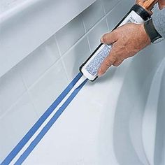 a person using a blue and white brush to clean a bathtub