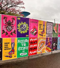 a fence covered in lots of colorful posters on the side of it's wall