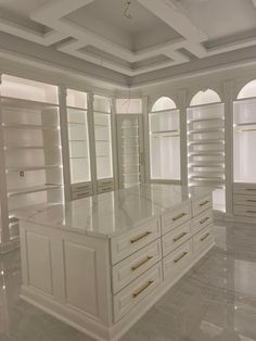 a large white kitchen with marble floors and cabinets in the center, along with built - in shelving