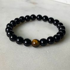 The beauty and wonder of the tiger eye bead culminate with a black onyx beaded bracelet. This is the perfect accessory for those who wish to evoke fearlessness, strength, and daring. The symbolism that these beads bear will ensure love and harmony no matter where you go. Wear this as your protection charm! The tiger eye bead is considered a power stone that can keep bad energy away. Black onyx beads are thought to promote emotional balance, which is why they've specially matched with the Tiger E Black Evil Eye Bracelet With 8mm Beads As Gift, Black Spiritual Evil Eye Bracelet With Round Beads, Black Evil Eye Bracelet With 8mm Beads For Gift, Spiritual Black Evil Eye Bracelet With 8mm Beads, Spiritual Black Evil Eye Bracelet With Round Beads, Minimalist Black Onyx Beaded Bracelets, Black Evil Eye Bracelet With Round Beads As Gift, Minimalist Black Beaded Bracelet With Natural Stones, Minimalist Black Beaded Bracelets With Natural Stones