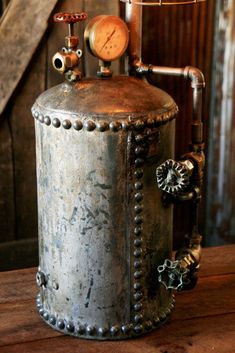 an old metal tank sitting on top of a wooden table next to a light fixture