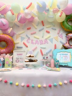 a table topped with donuts and balloons next to a wall covered in confetti