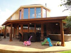 an outdoor patio with toys and furniture on the ground in front of a large house