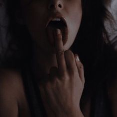 a woman laying in bed with her hand on her mouth and finger to her lips