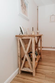 a wooden table sitting on top of a hard wood floor next to a white wall