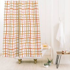 a bathroom with a bathtub, shower curtain and potted plant on the floor