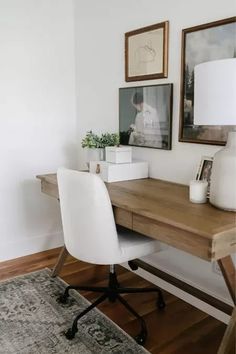 a wooden desk with white chairs and pictures on the wall