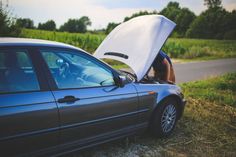 a car that has its hood open on the side of it's head and is parked next to a road